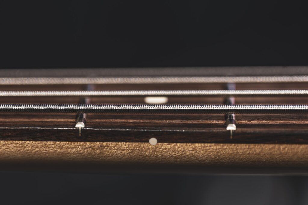 Close-up of strings on the fretboard of a bass guitar.