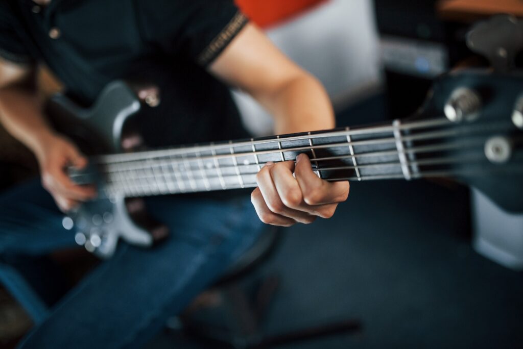 Close up view of musician plays bass guitar indoors